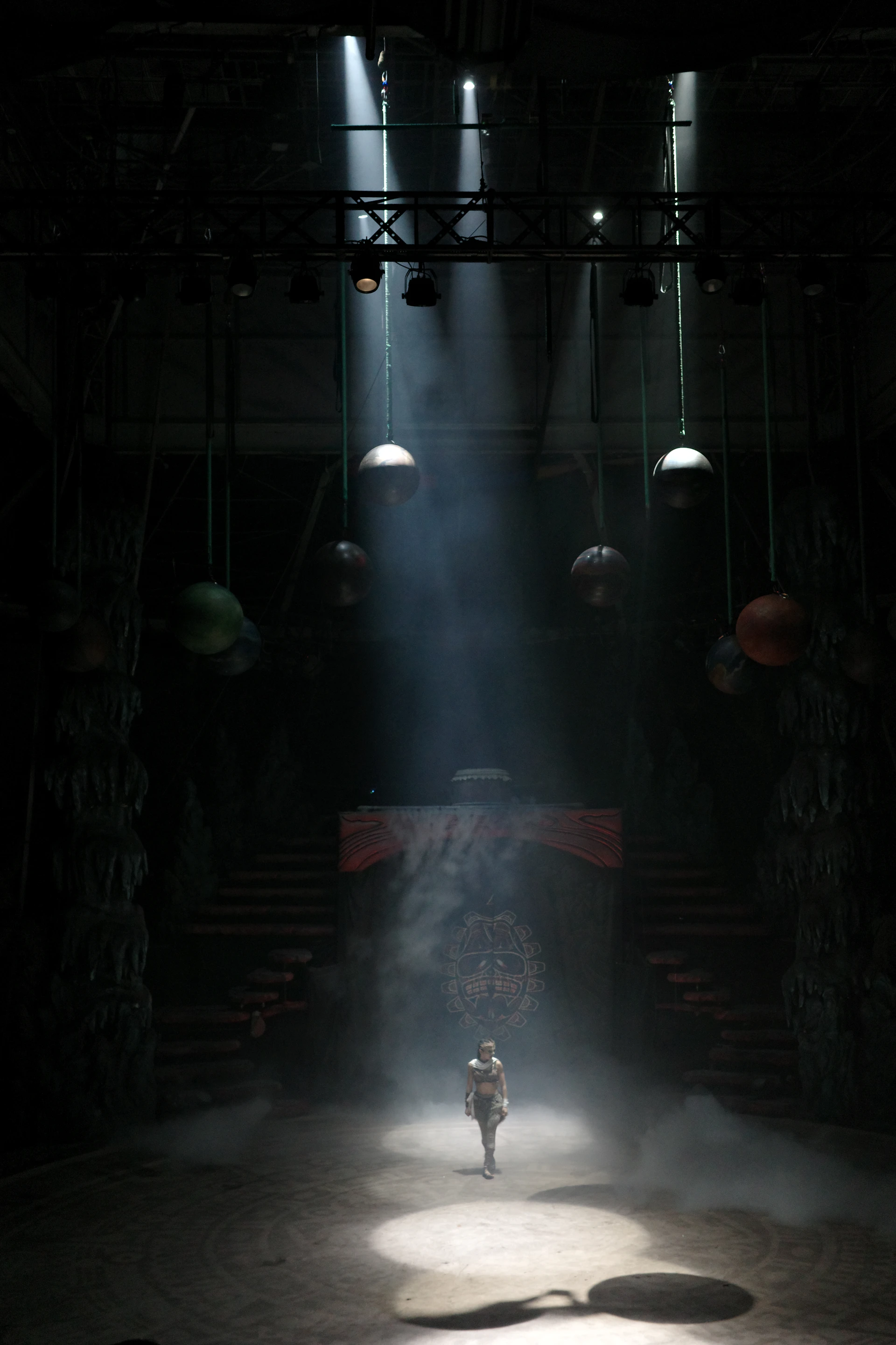 A lone figure stands on a dimly lit stage.