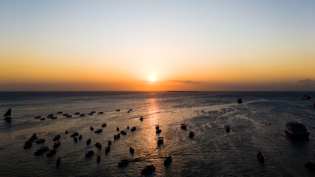 Sunset over a calm ocean with many boats