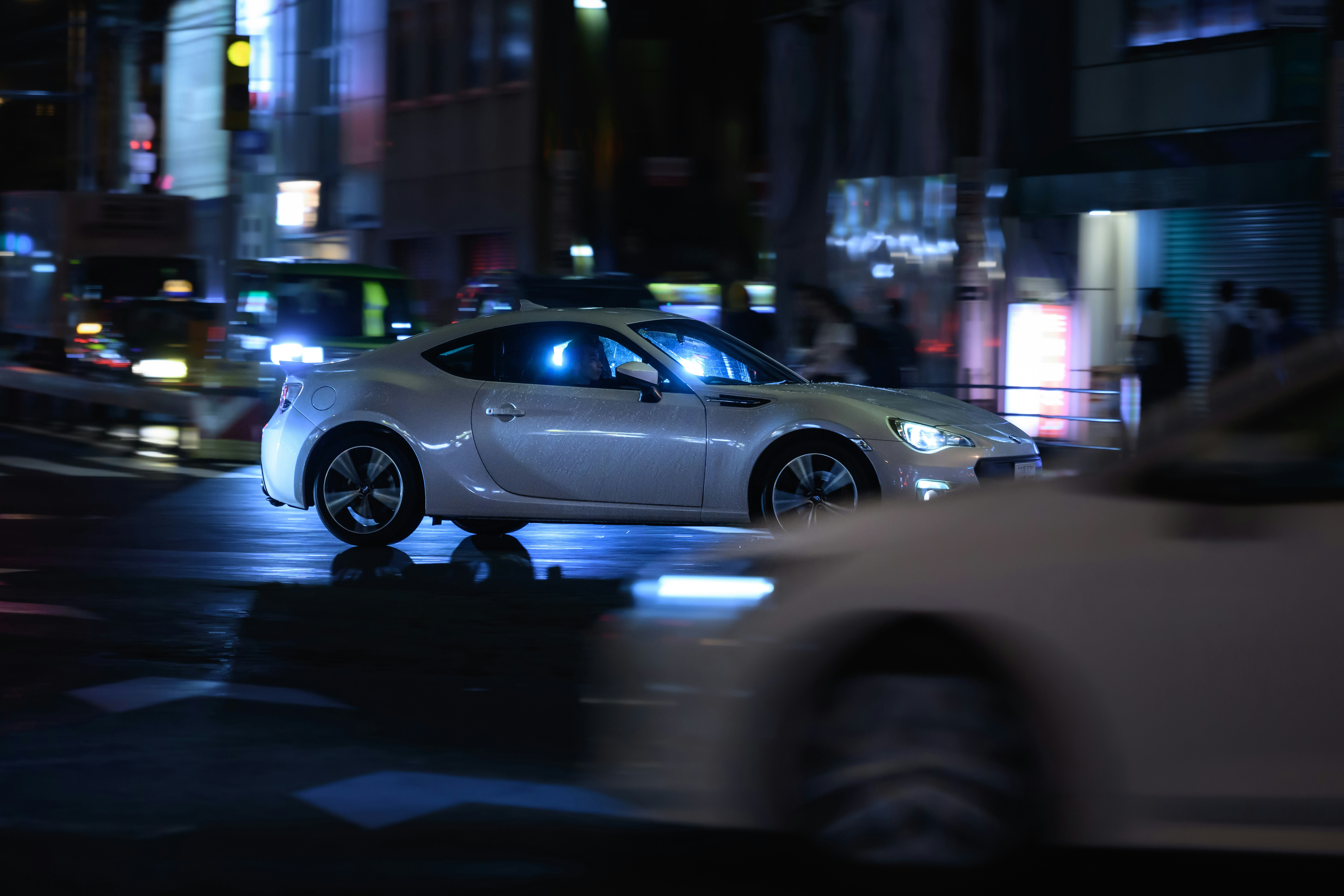 White sports car driving through city at night