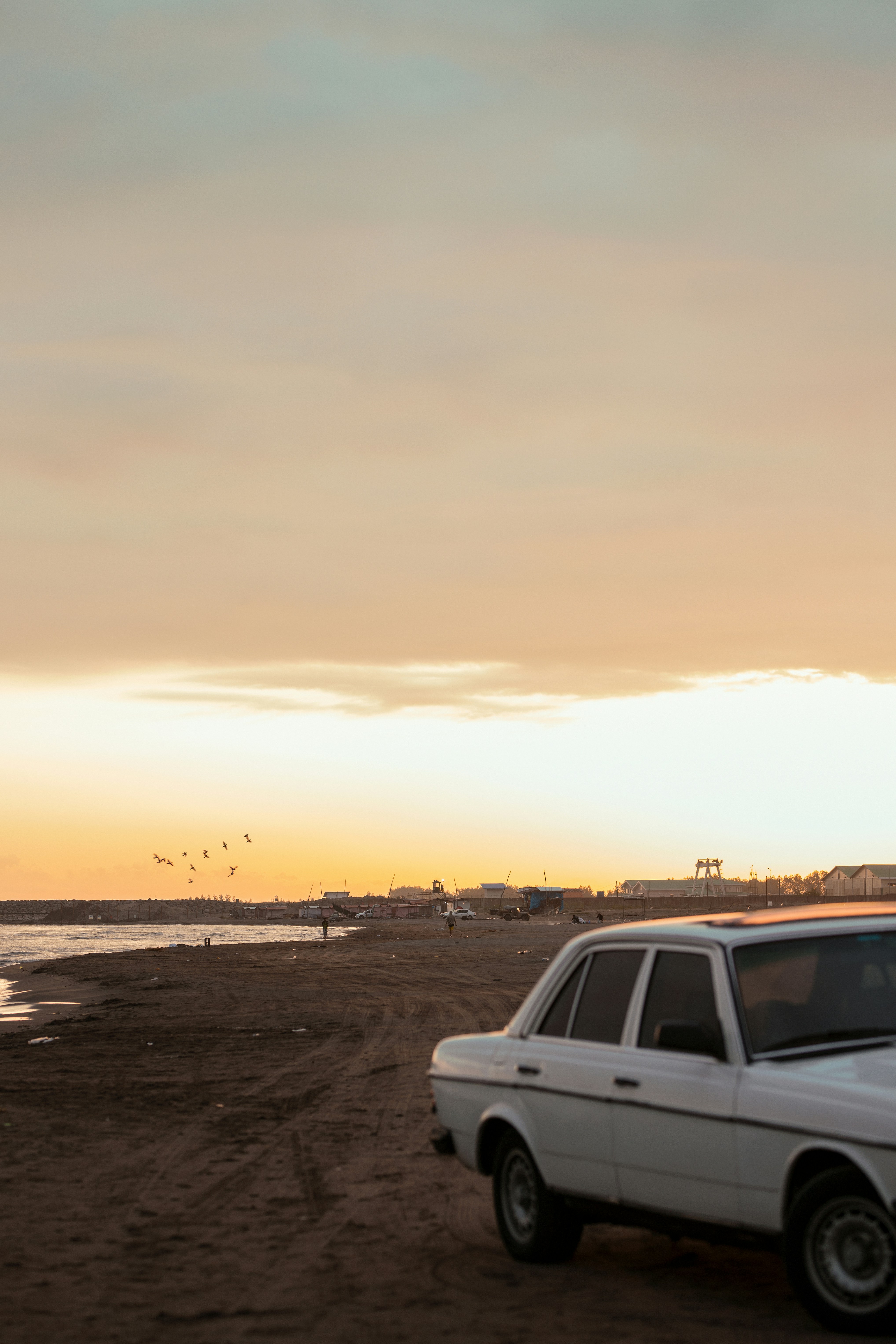 Coche blanco aparcado en una playa al atardecer