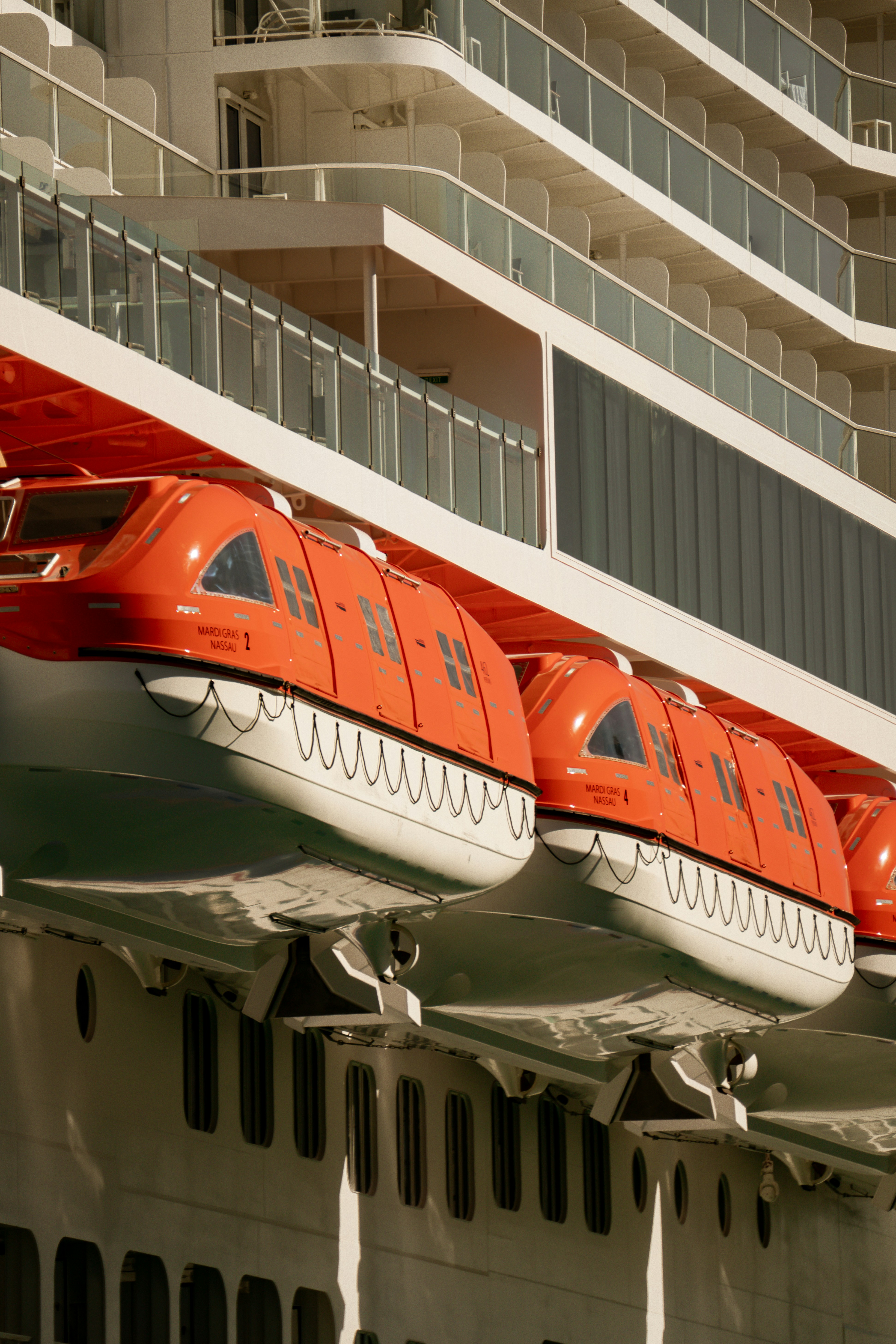 Orange lifeboats attached to a large white ship.