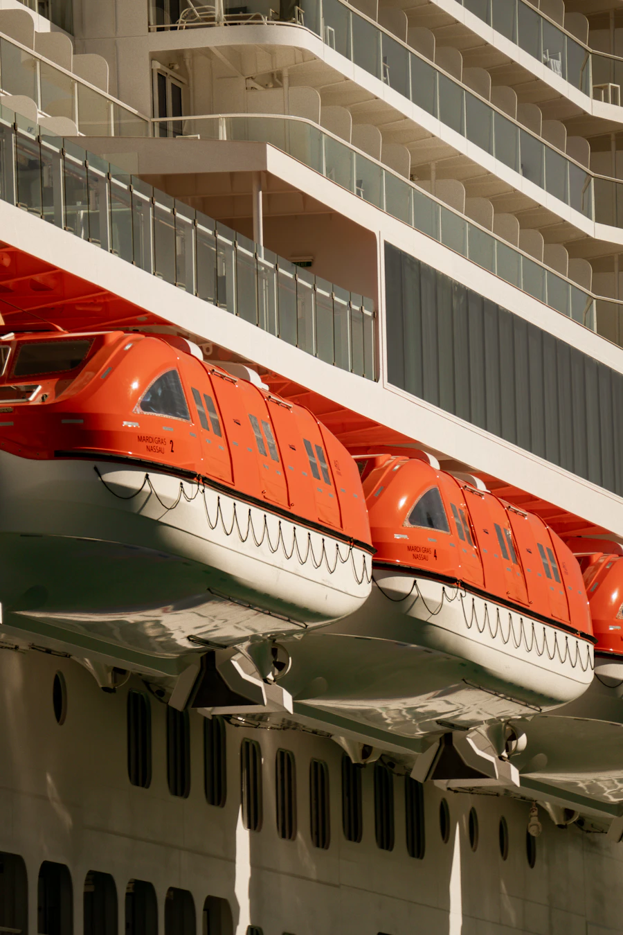 Orange enclosed lifeboats mounted on the side of a large white ship