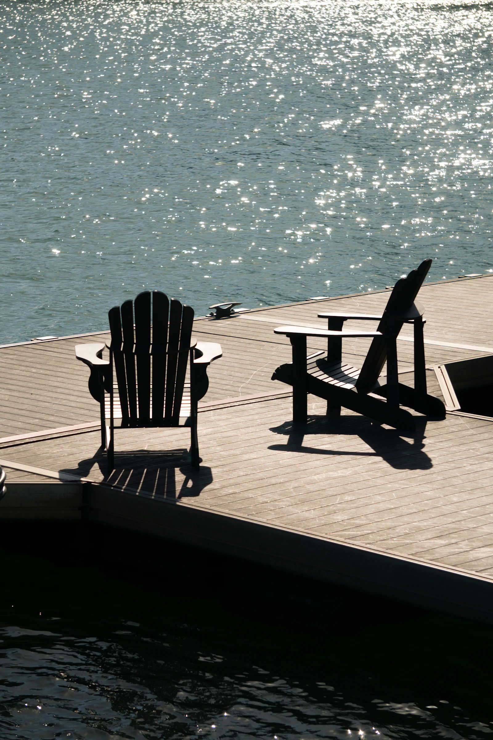 Two Adirondack chairs on a dock over the water