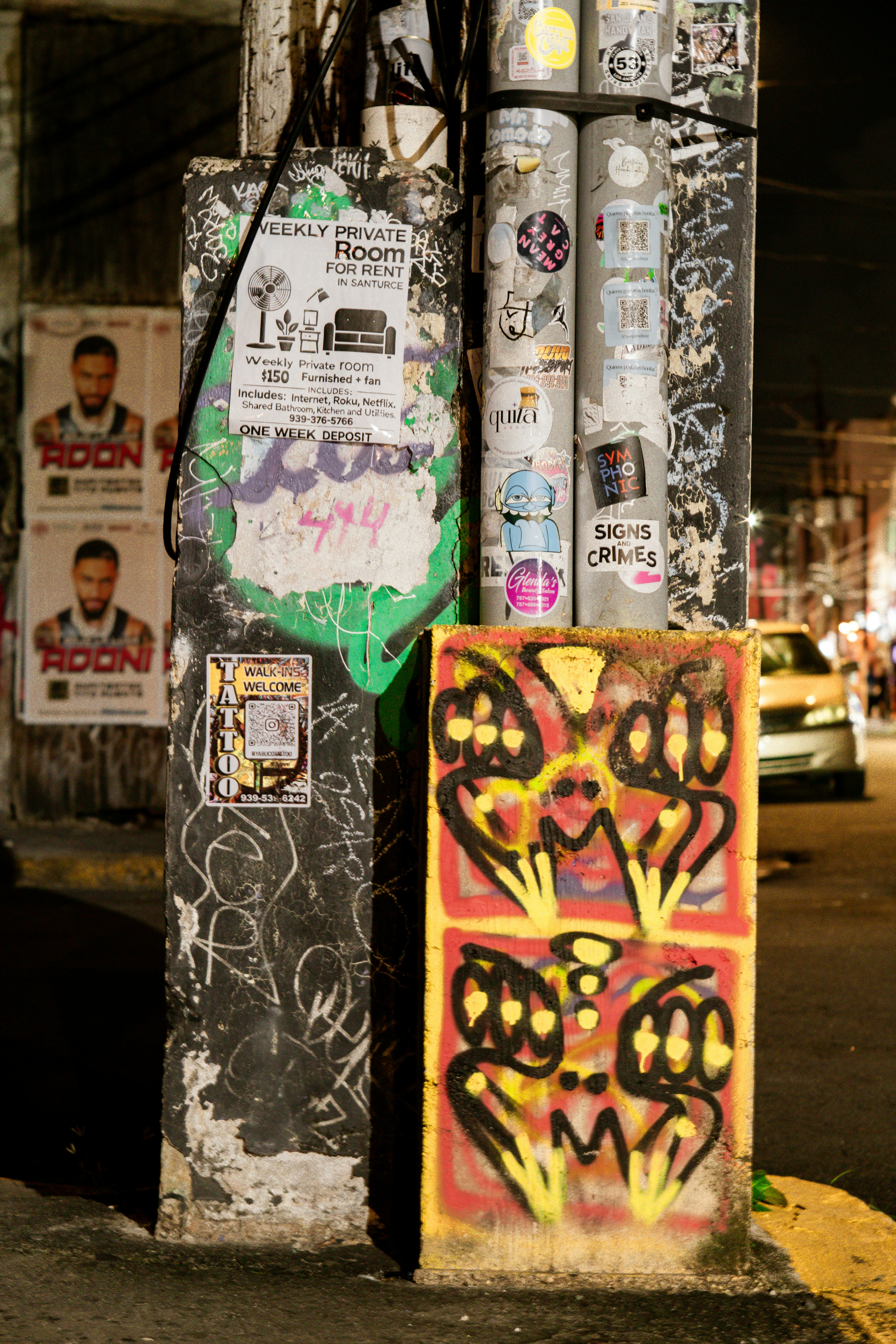 Graffiti-covered utility pole with posters and stickers.