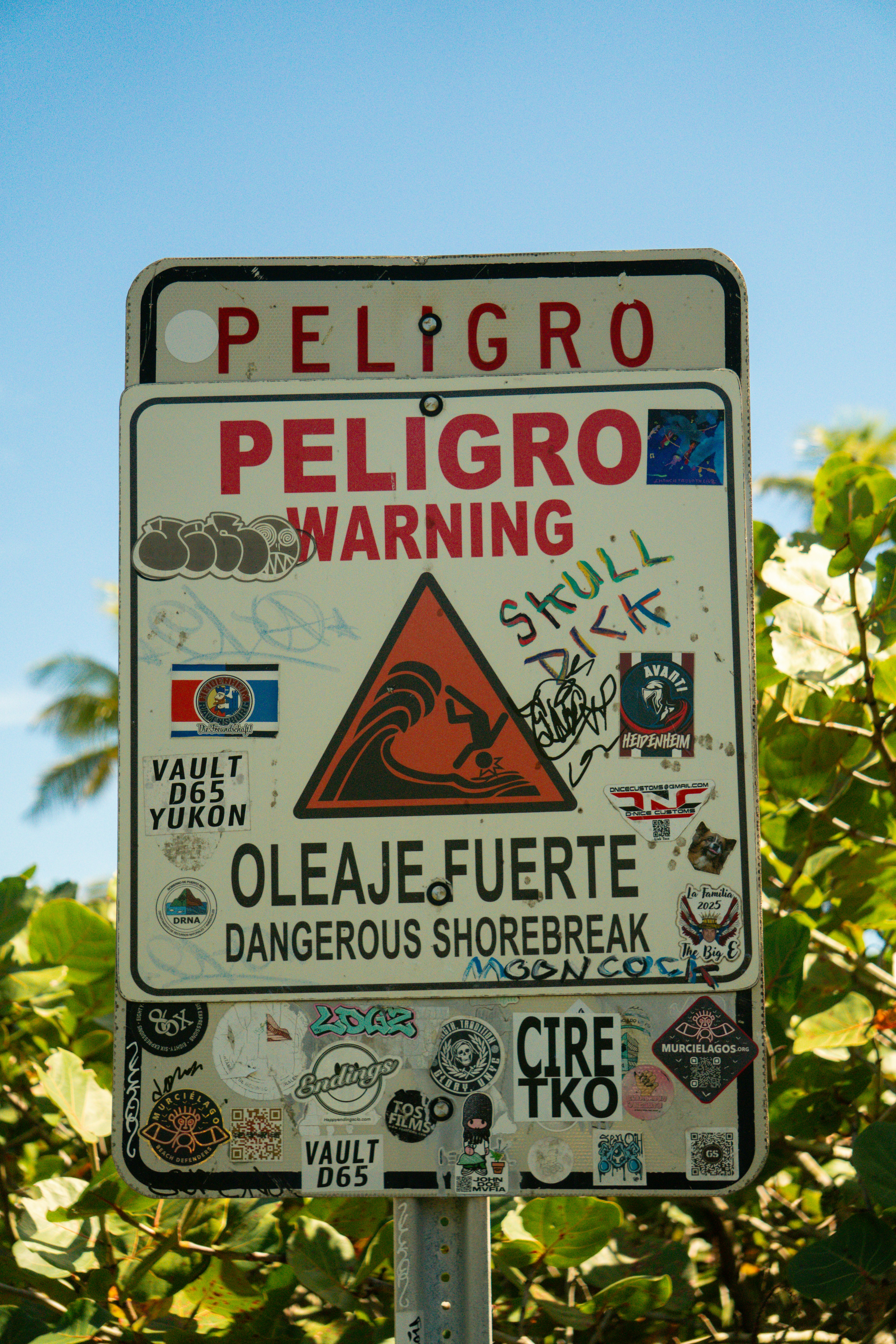 Warning sign for dangerous shorebreak with stickers