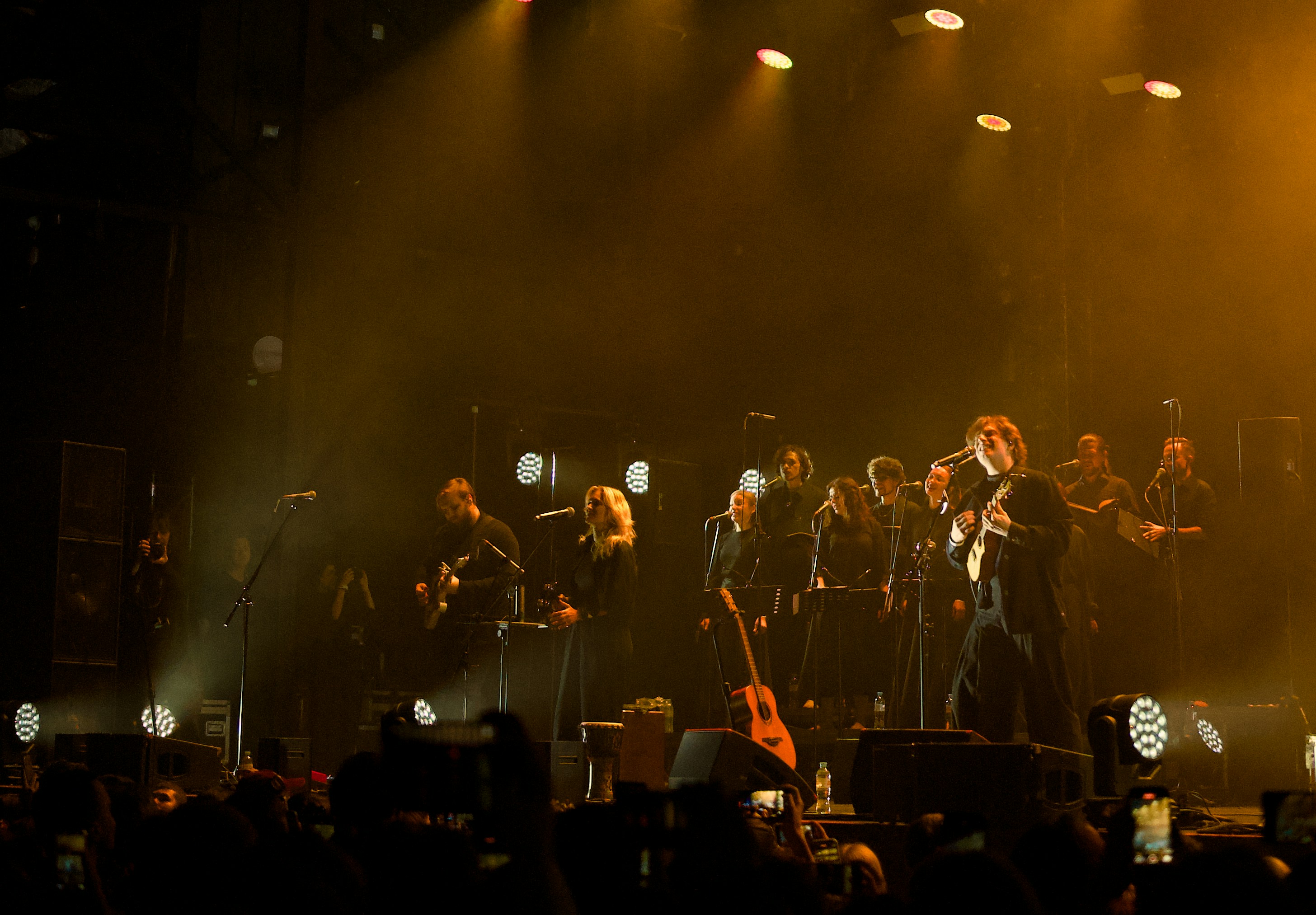 A band performs on a brightly lit stage at night.