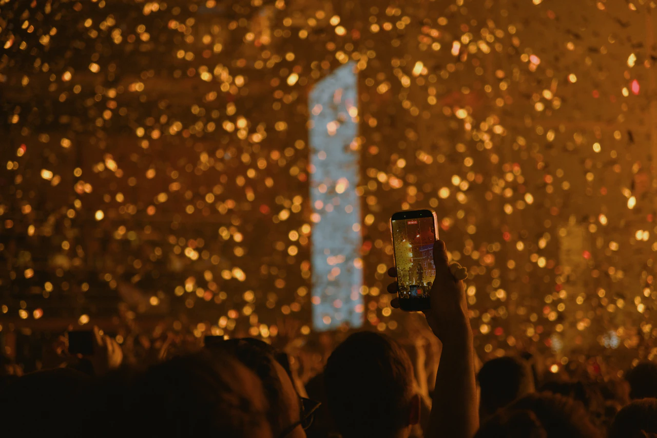 Golden confetti falling over crowd holding phones at an event