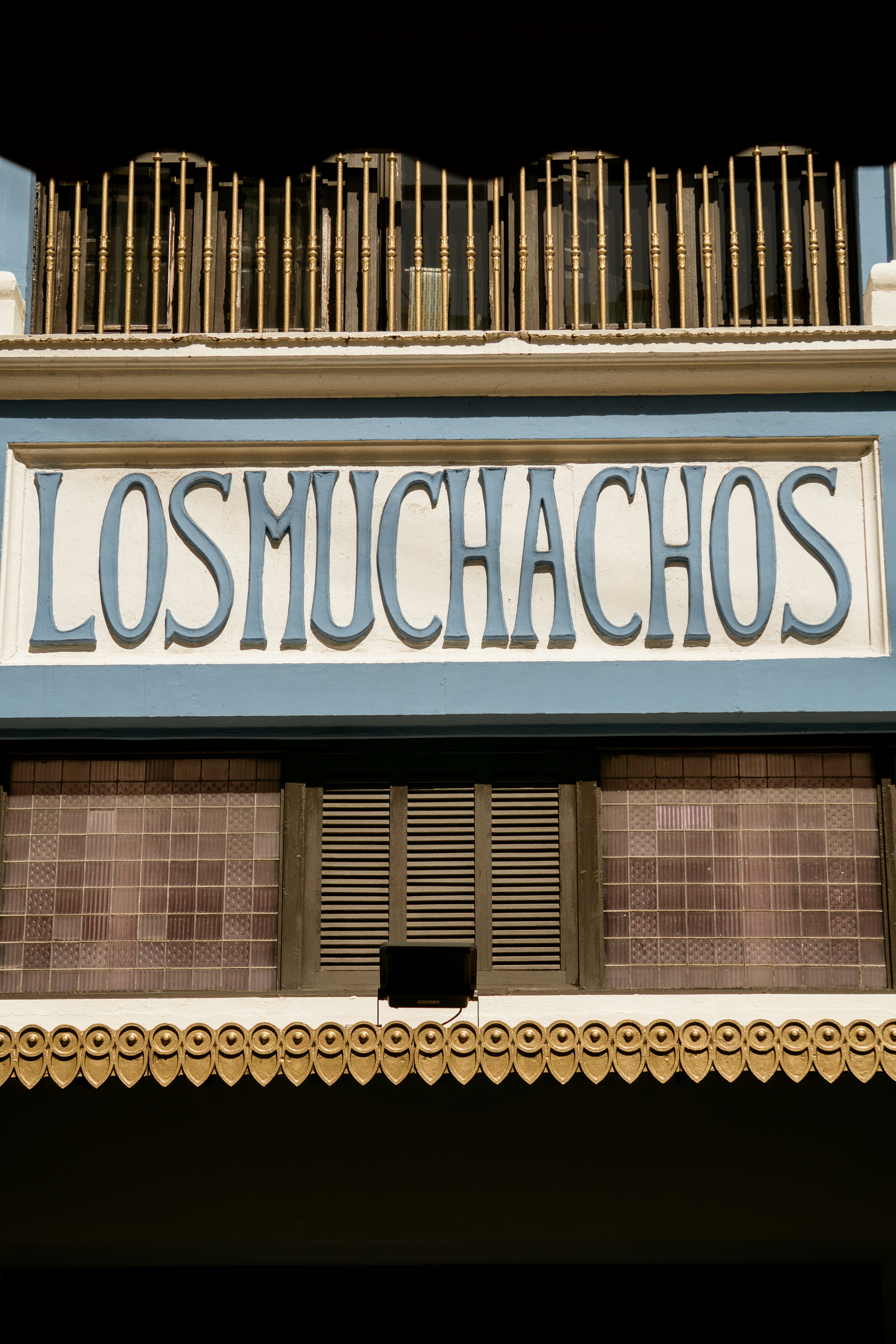Sign for los muchachos above tiled windows