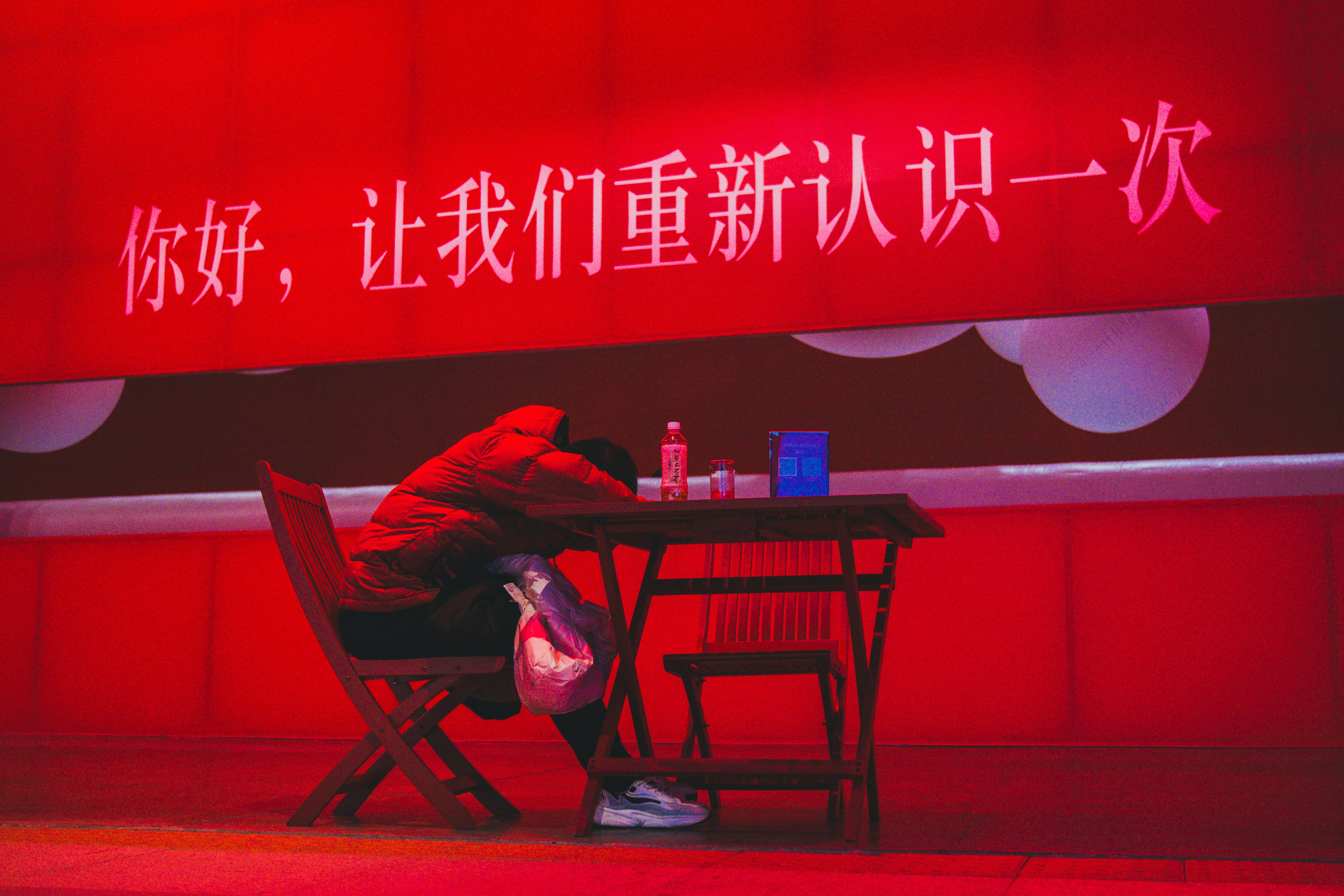Person slumped over a table with red banner.