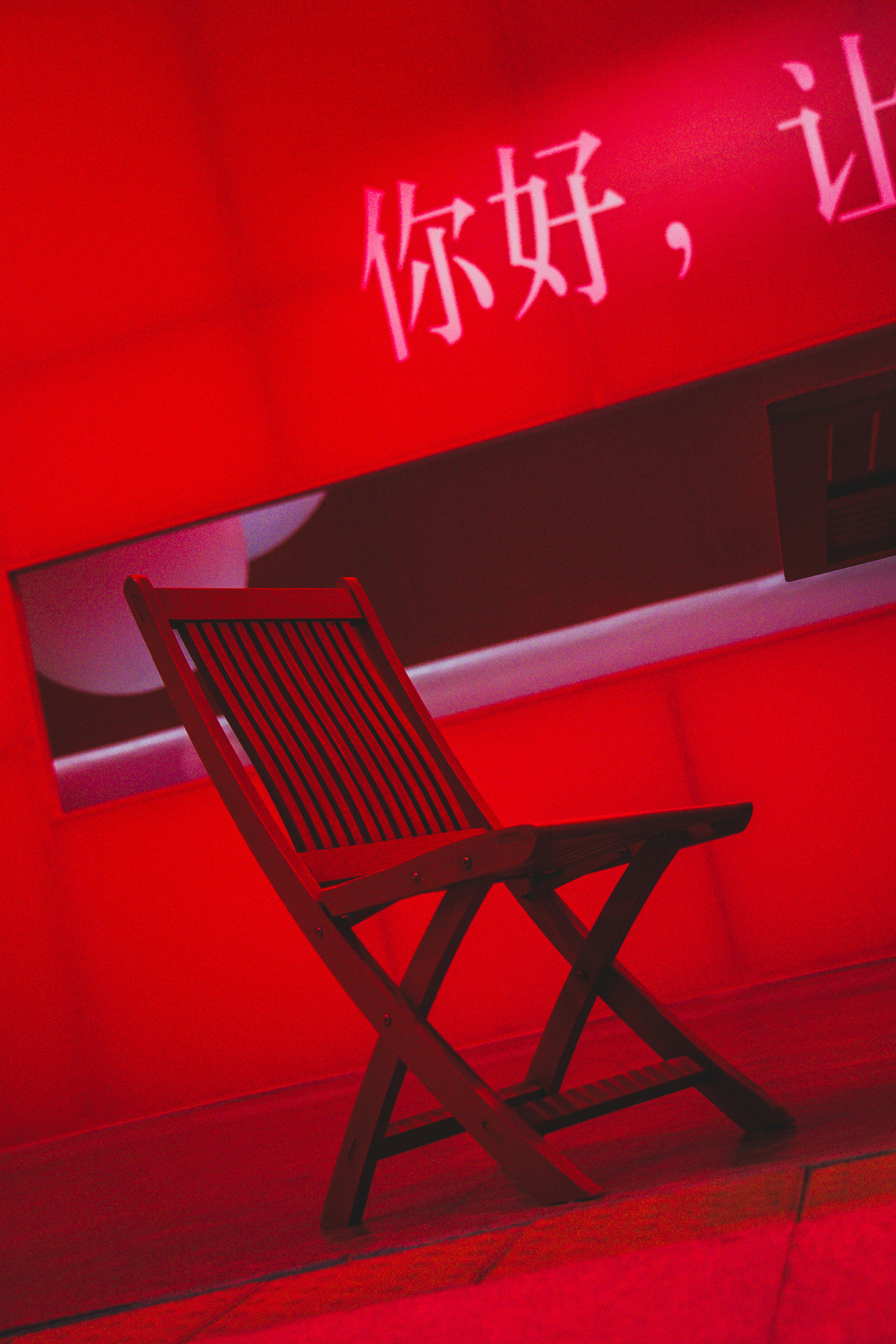 Wooden chair against a red wall with chinese text.