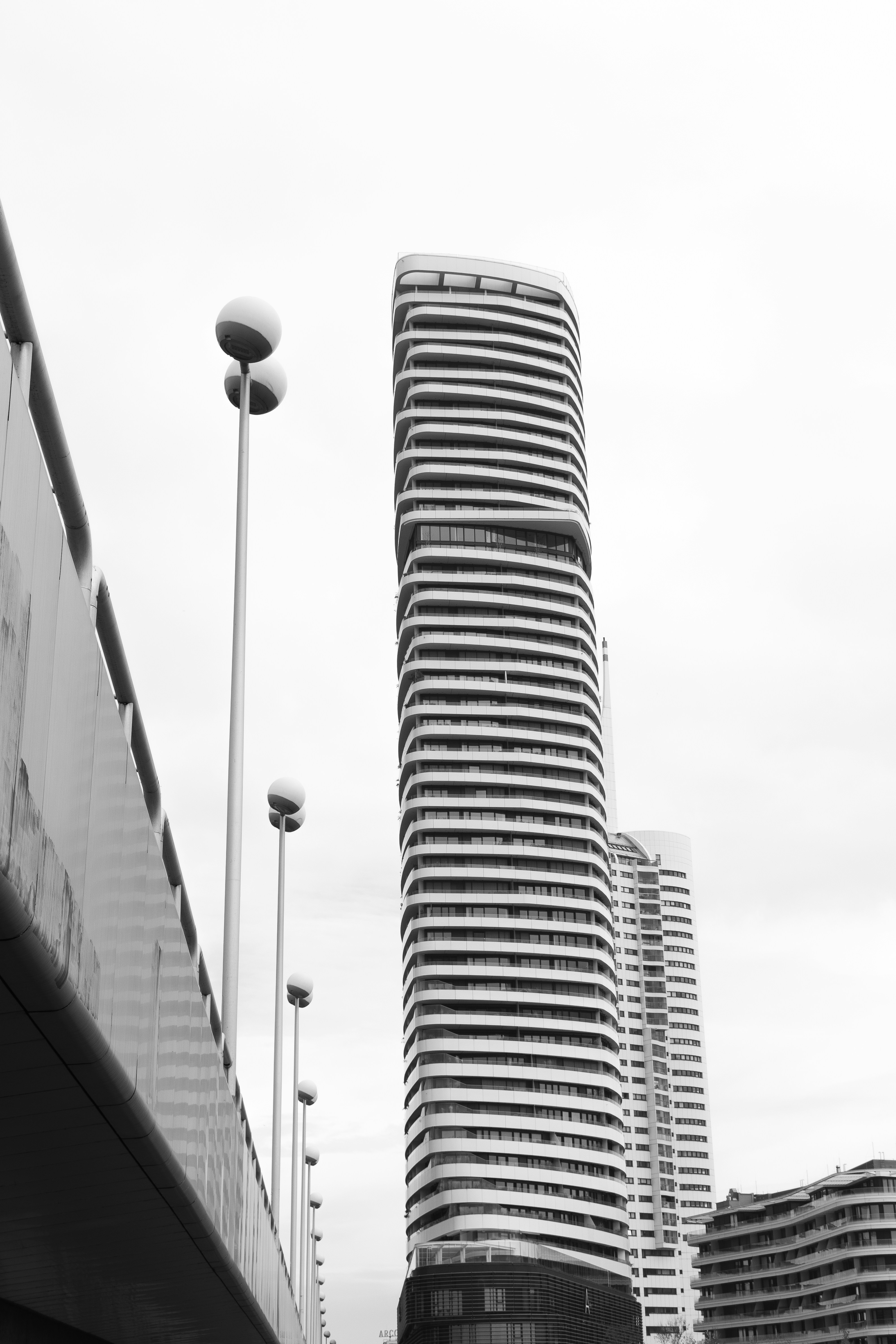Modern skyscraper with curved balconies against cloudy sky
