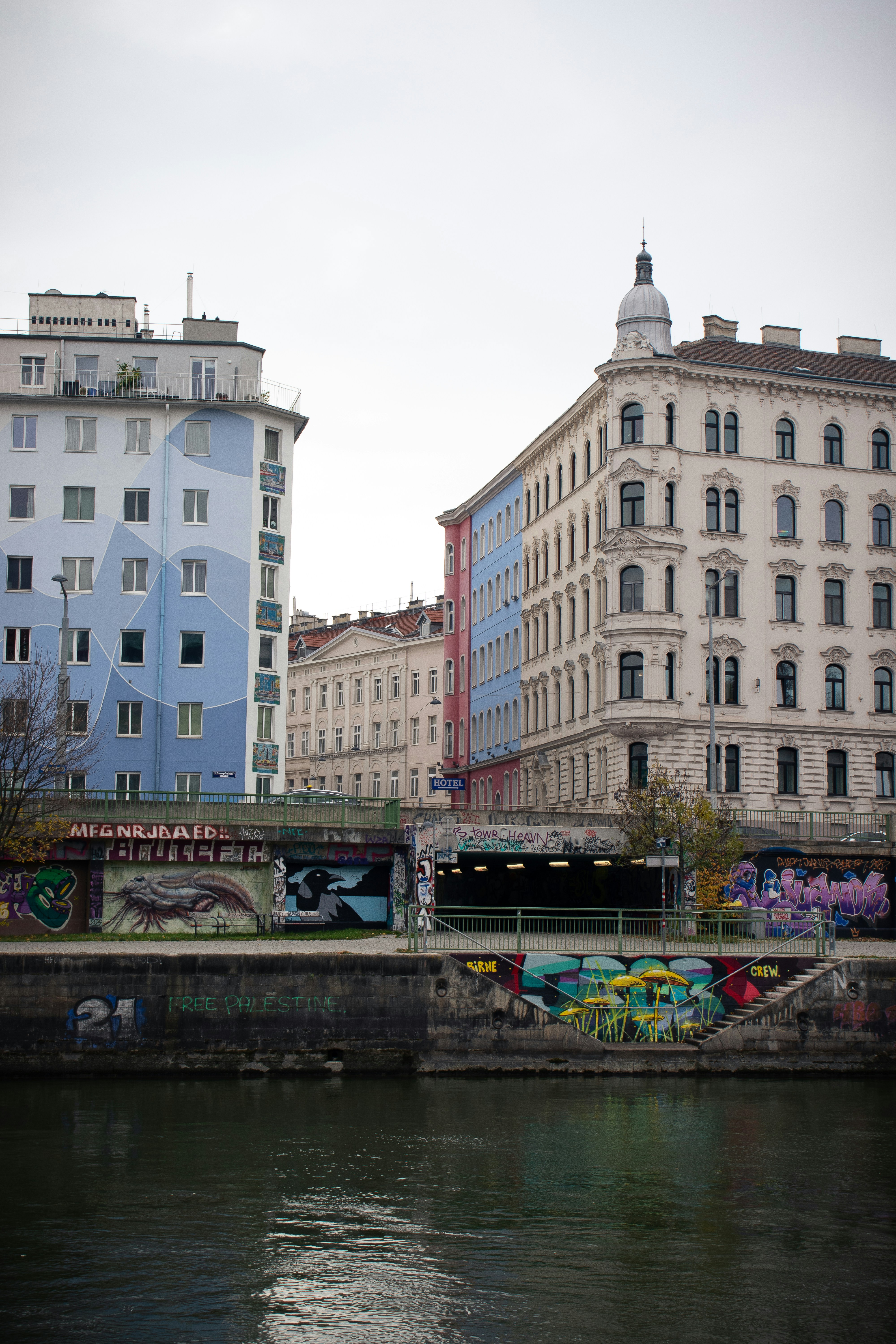 Buildings line a canal with graffiti art.