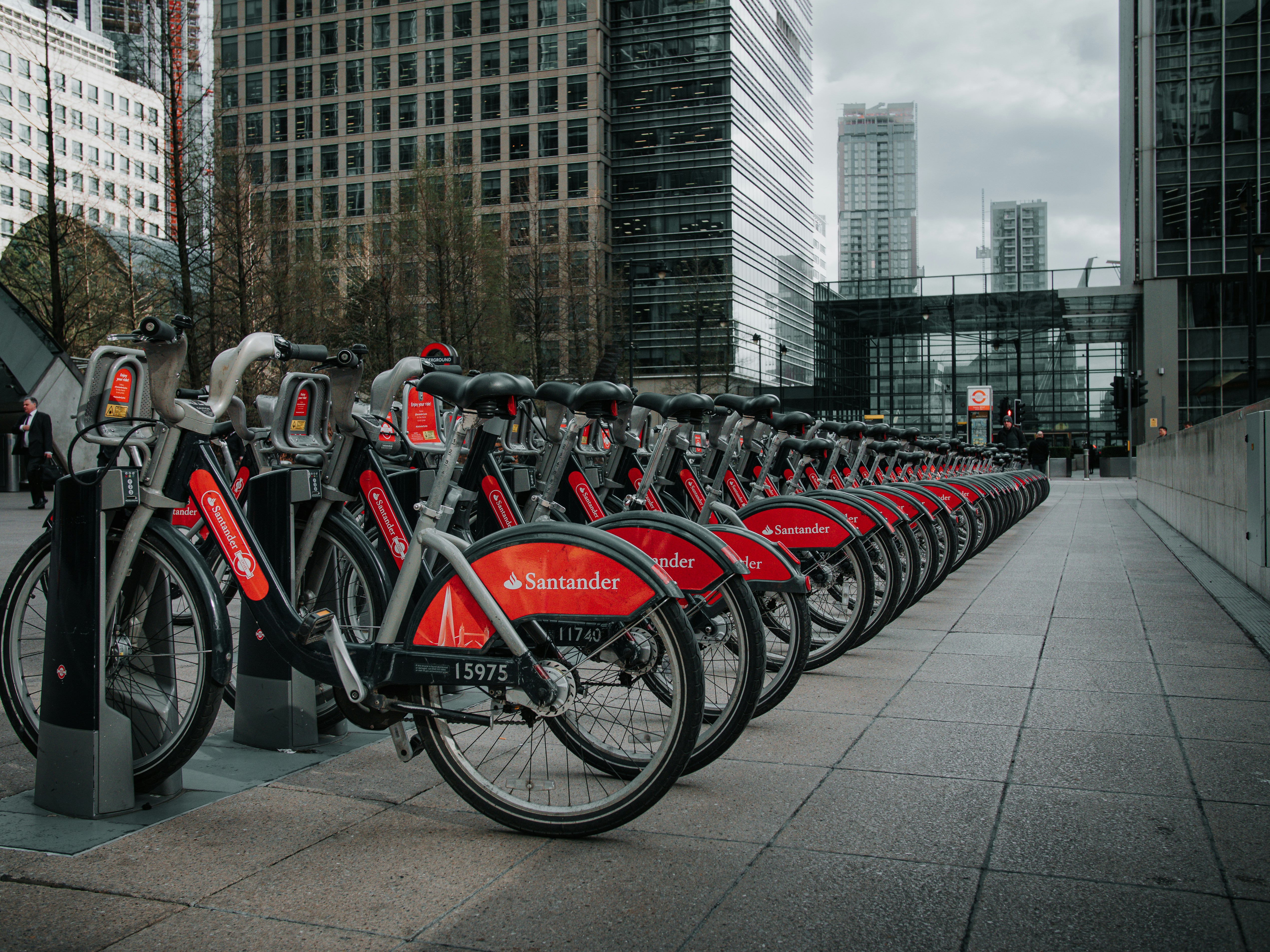 Fila di biciclette rosse a noleggio parcheggiate ordinatamente fuori dagli edifici