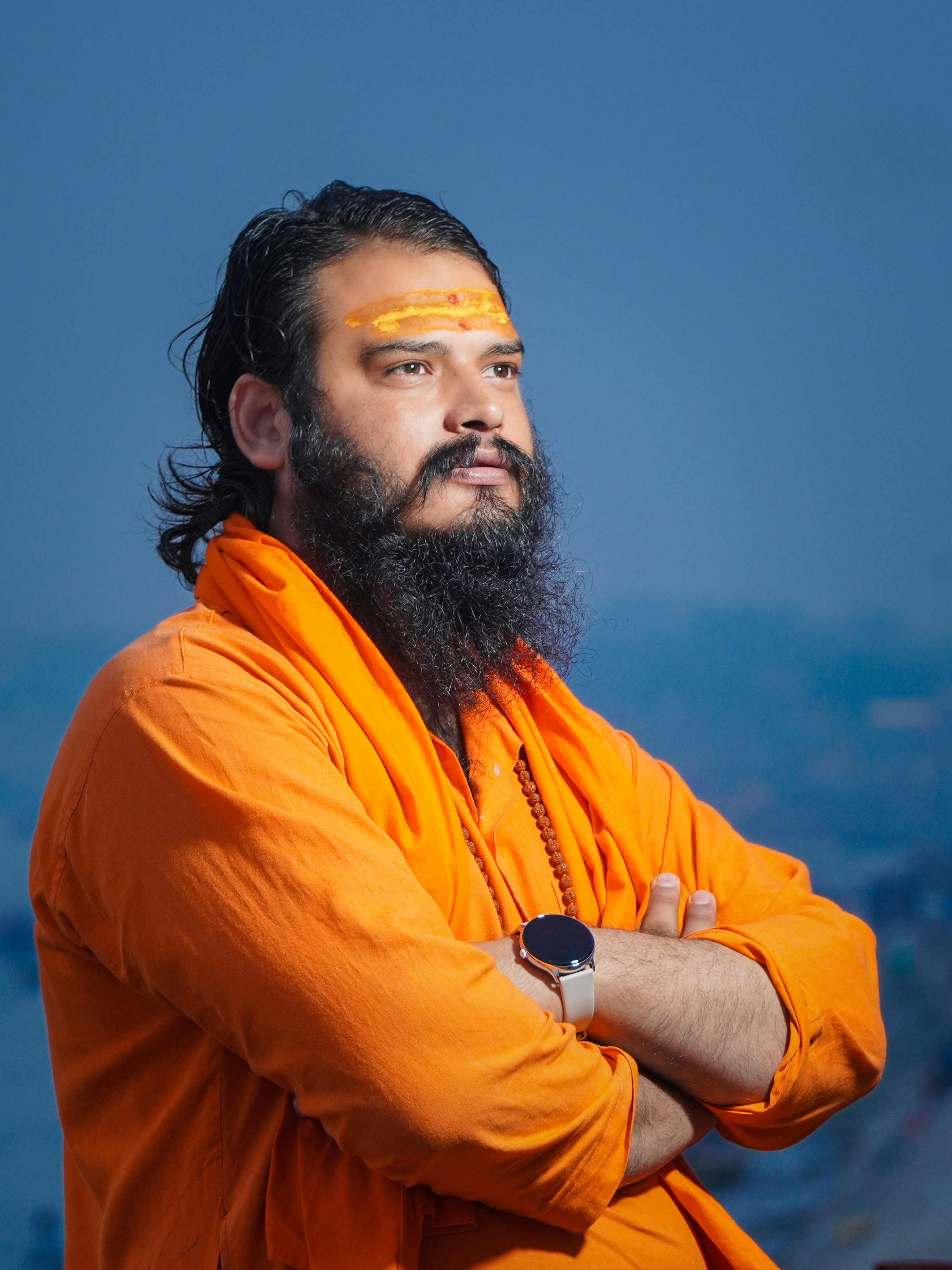 Man with beard and orange robes looks away