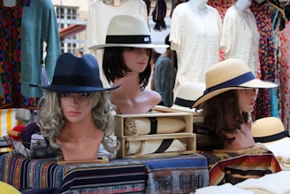 Mannequins wearing hats at an outdoor market.