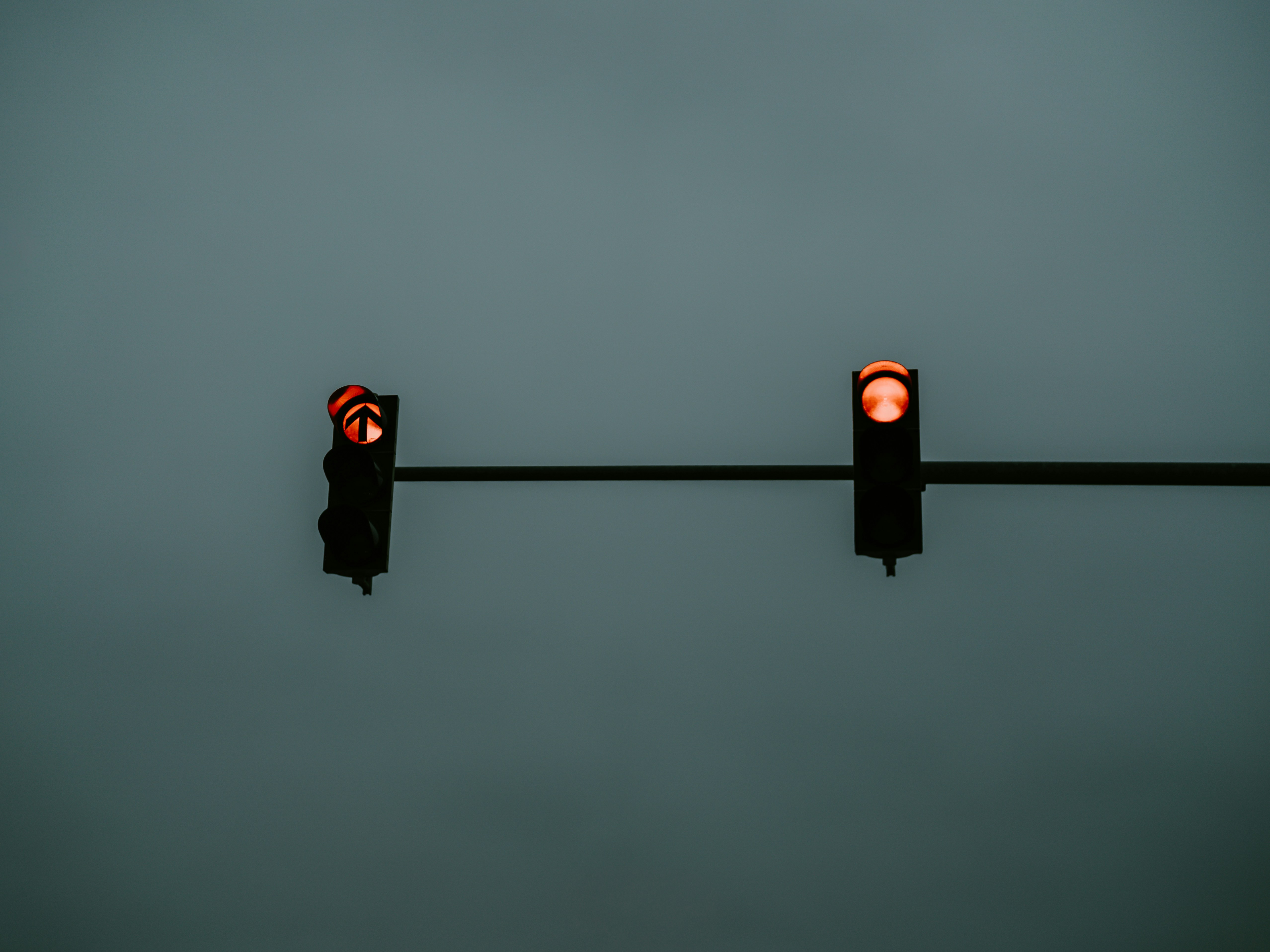 Due semafori illuminati di rosso contro il cielo