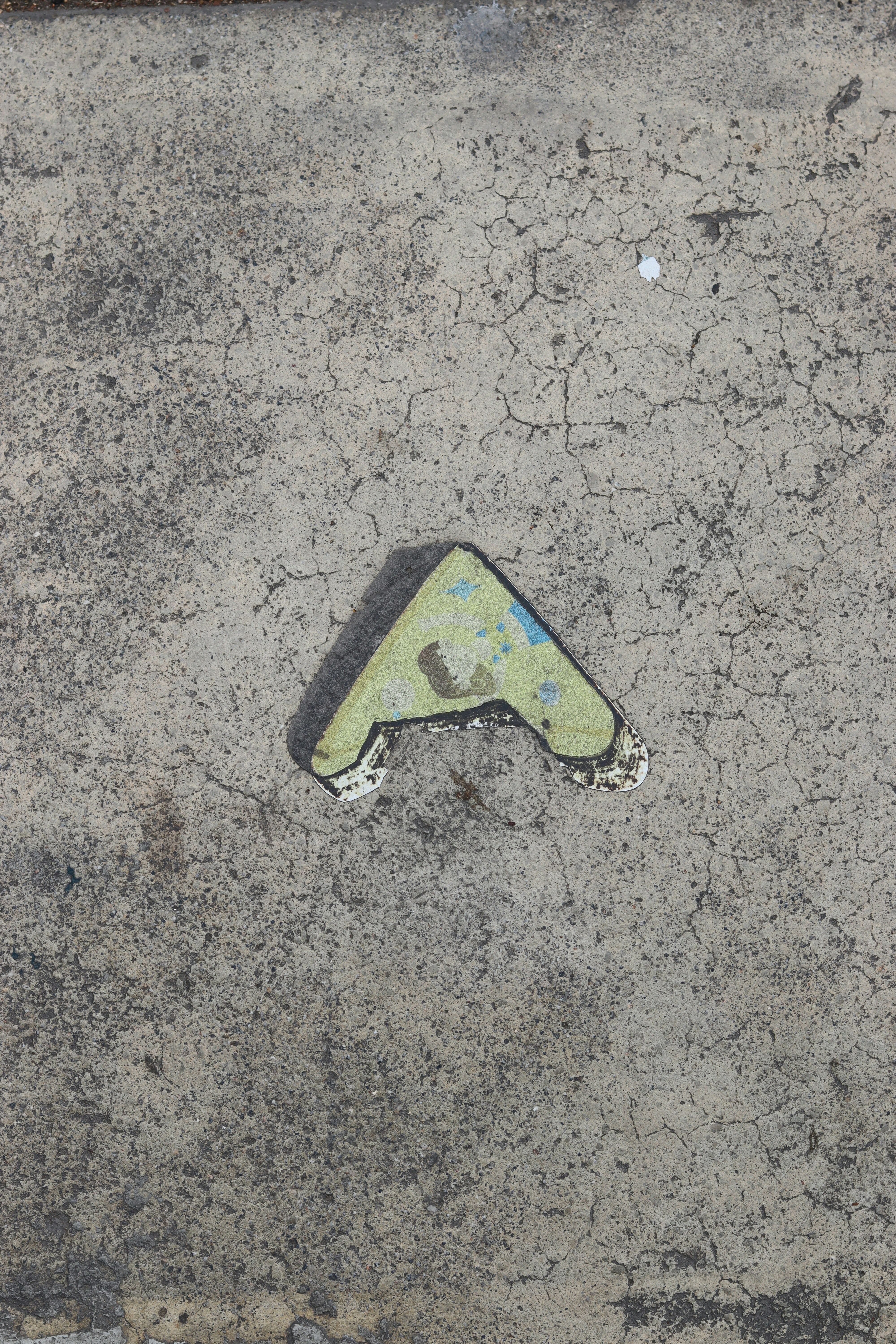 Arrow painted on cracked concrete pavement