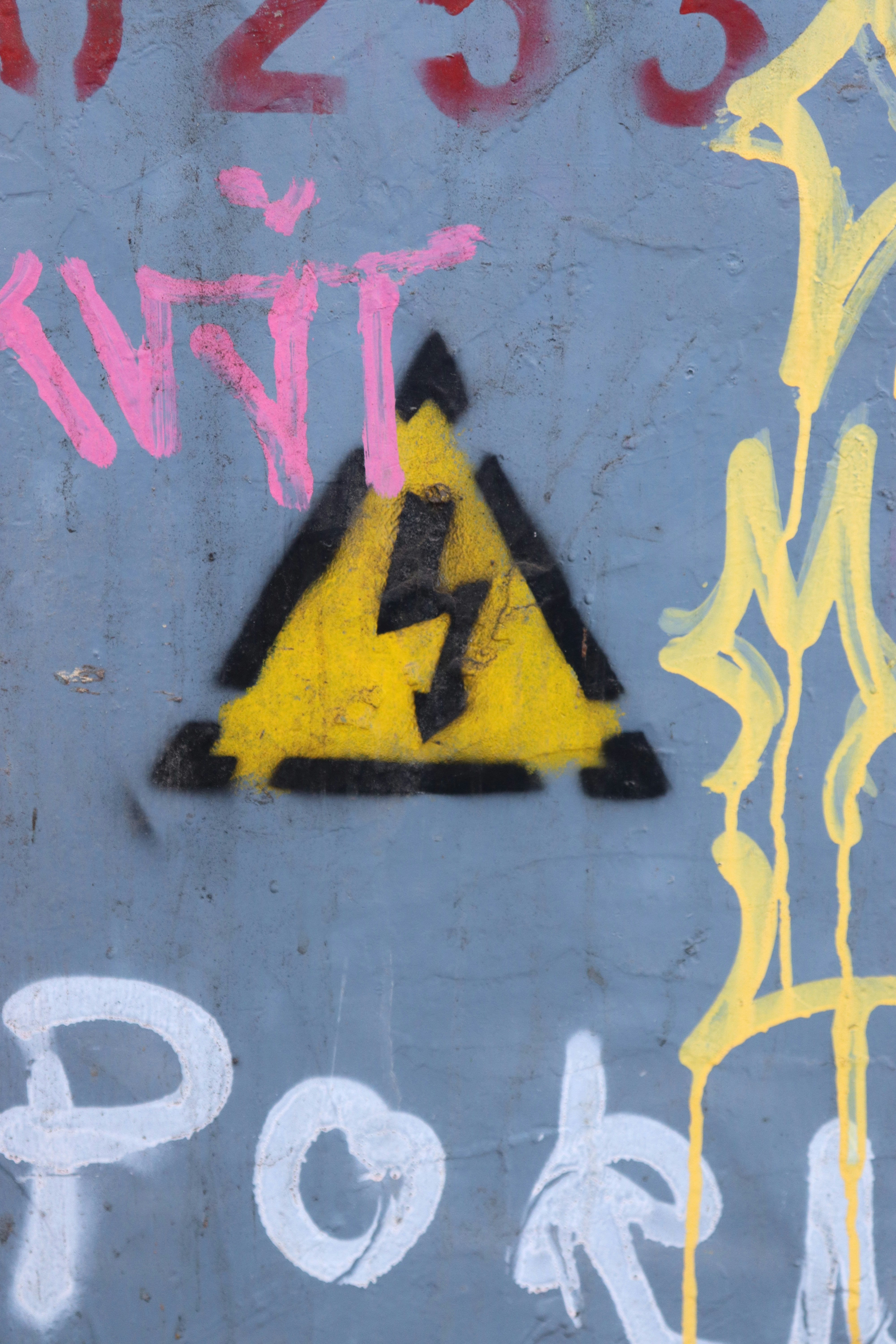 Yellow triangle with lightning bolt symbol and graffiti