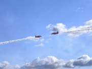 Two red jets flying in formation leaving smoke trails.