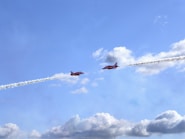 Two red jets flying in formation leaving smoke trails.