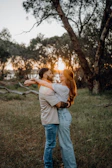 Couple embracing outdoors at sunset with trees