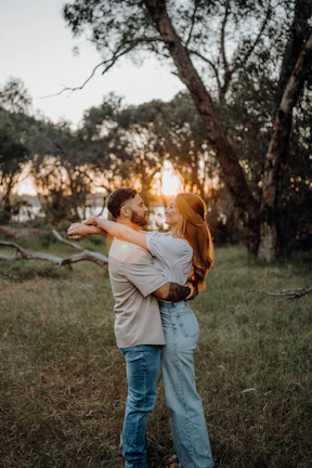 Couple embracing outdoors at sunset with trees