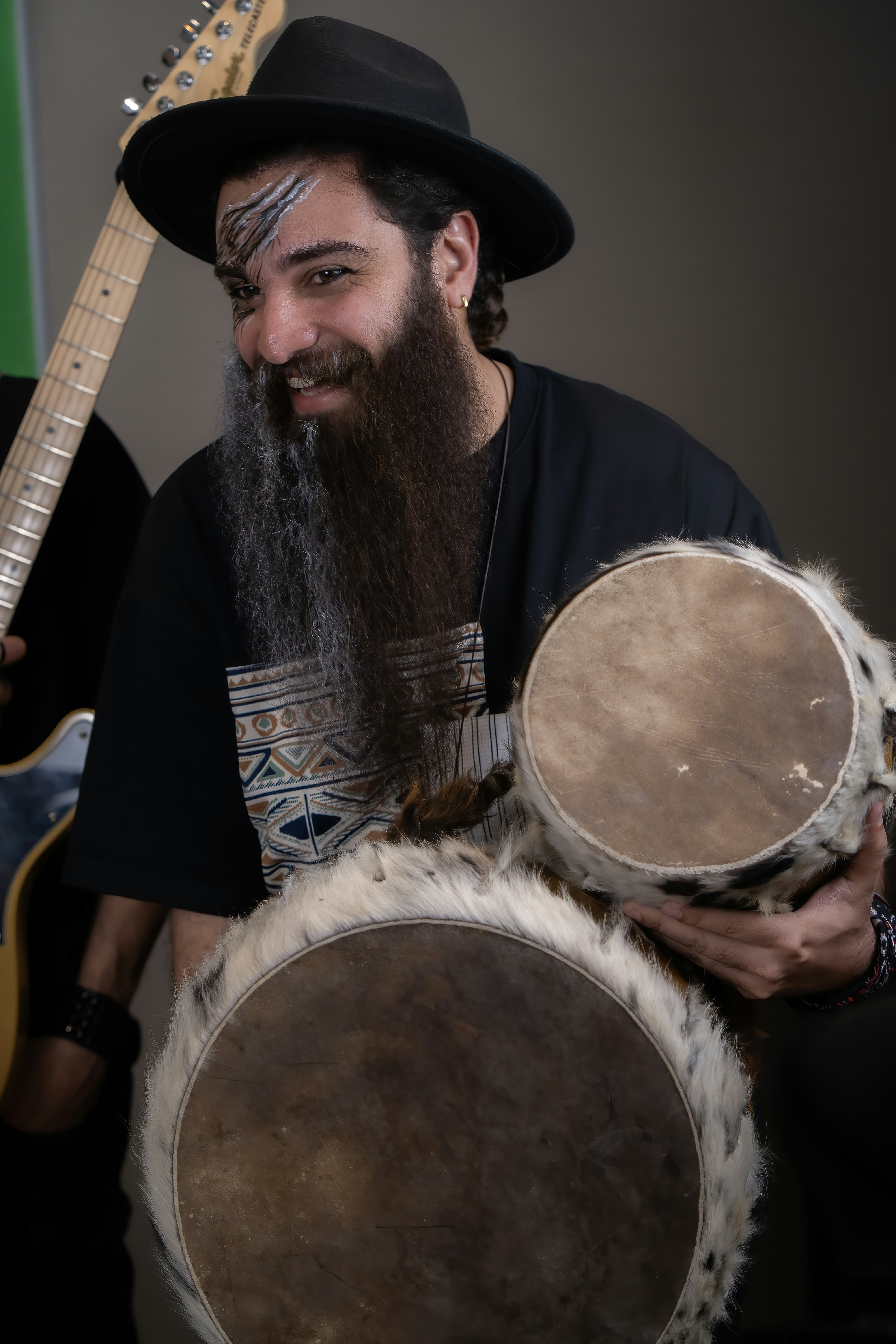 Man with beard and face paint plays drums