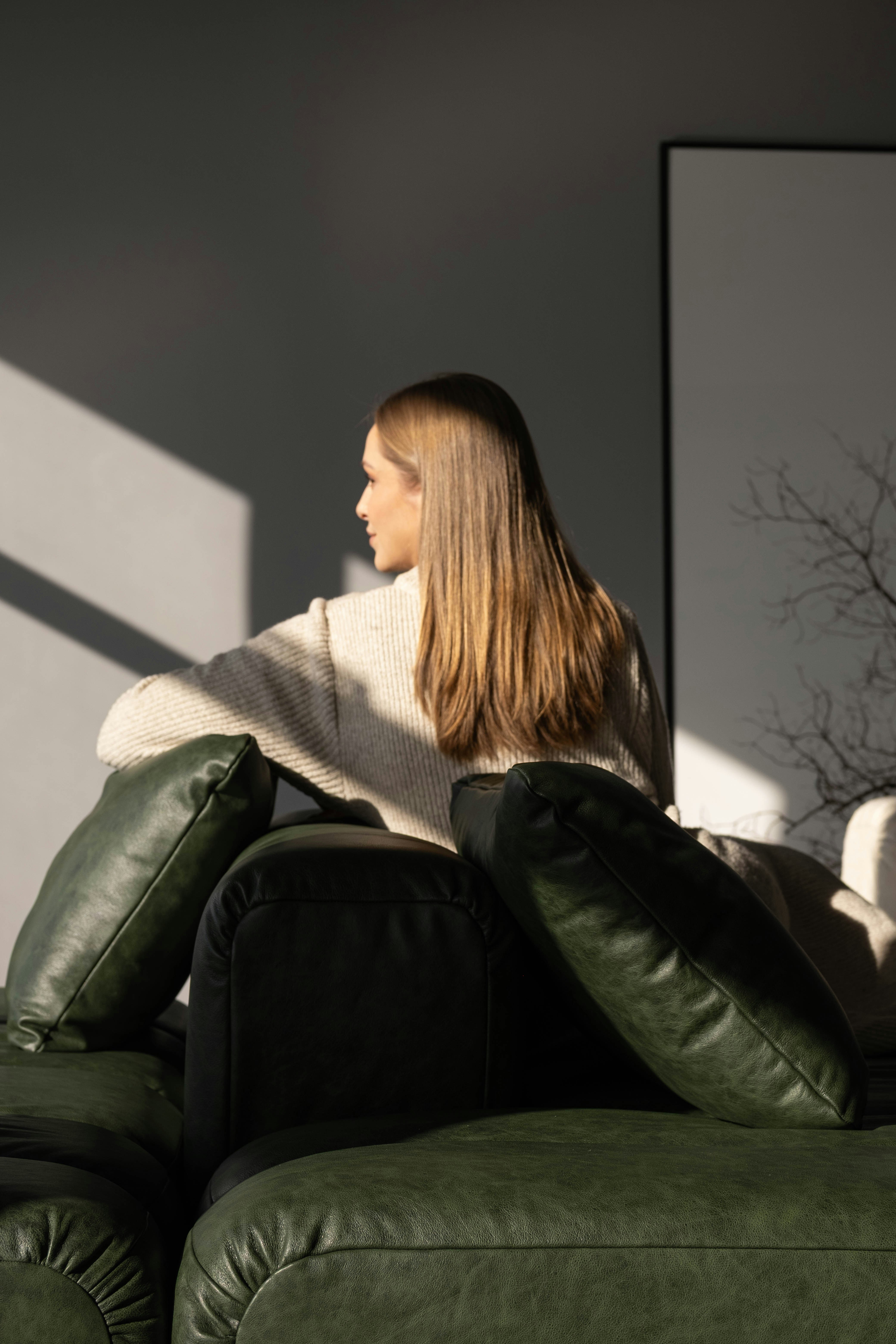 Woman sitting on a couch with sunlight.