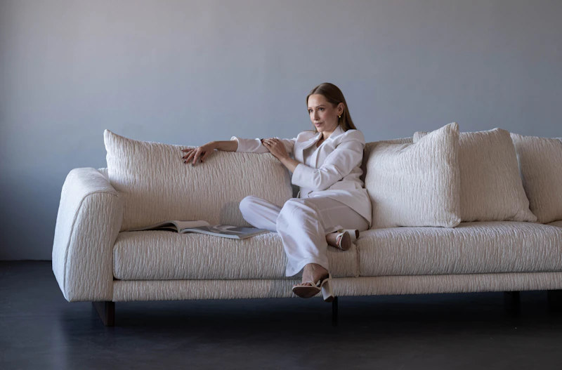 woman in white suit sitting on textured sofa