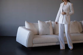 Woman in white suit standing by white sofa