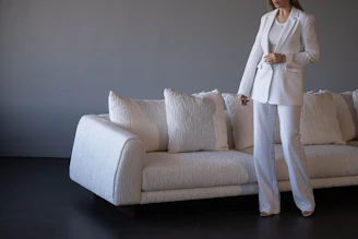 Woman in white suit standing by white sofa