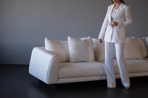 Woman in white suit standing by white sofa