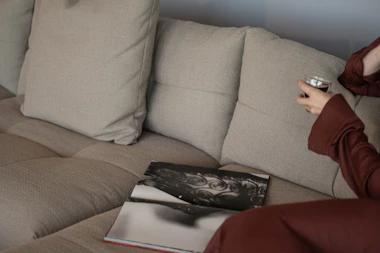 Person relaxing on a sofa with a drink and book