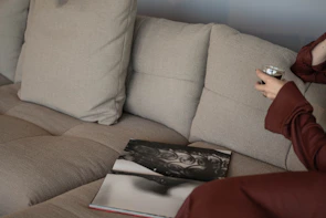 Person relaxing on a sofa with a drink and book