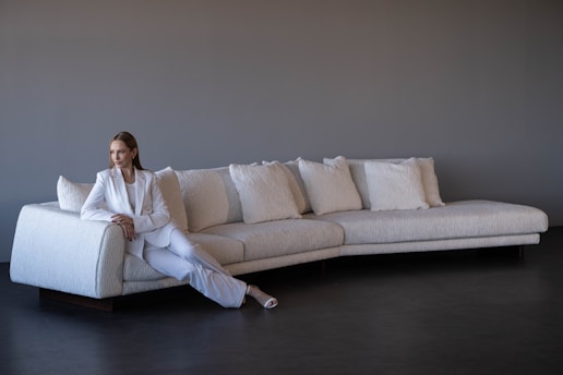 Woman in white suit sitting on a modern white sofa.