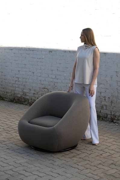 Woman standing next to a round, modern chair.