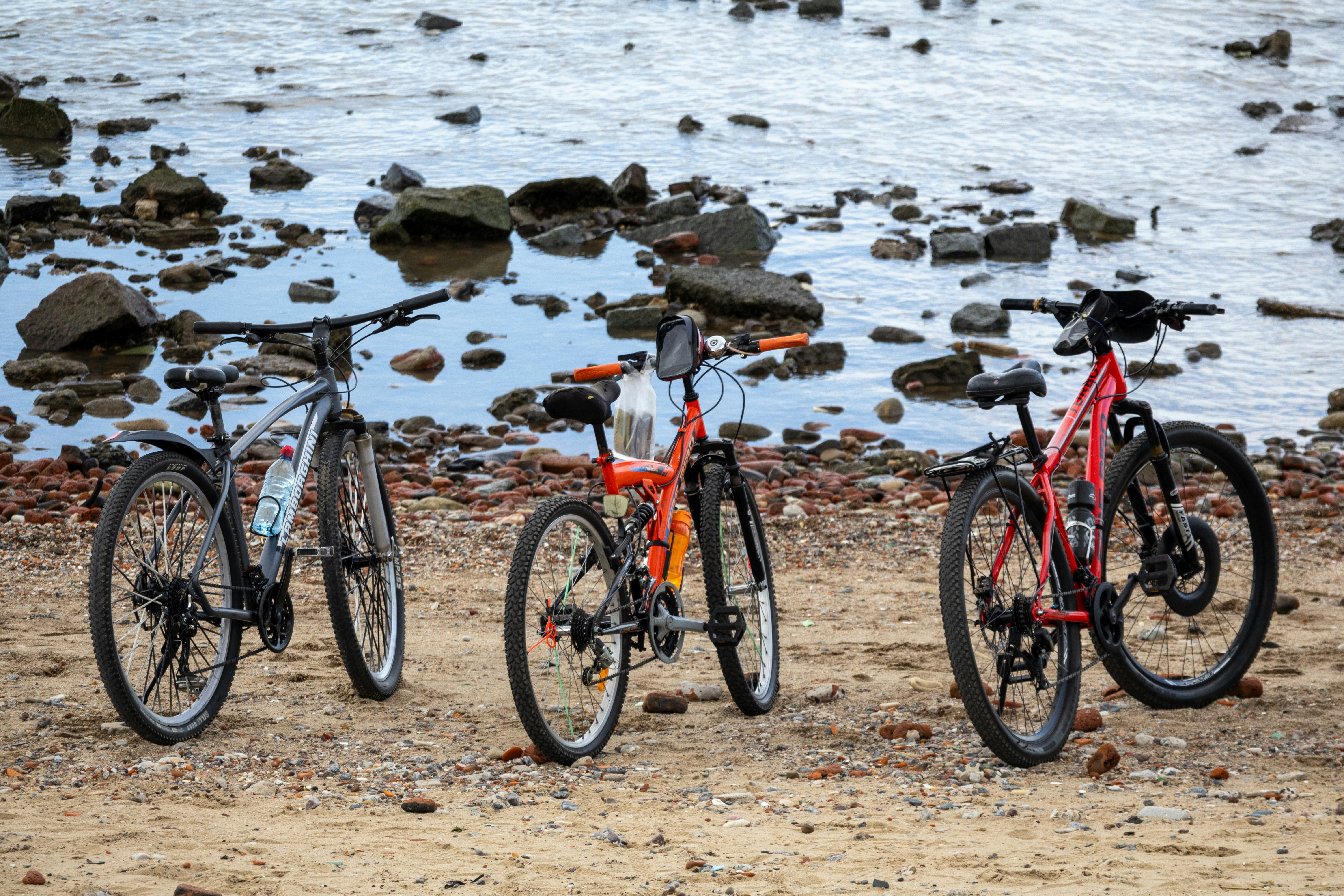 Three bicycles parked on a rocky beach.