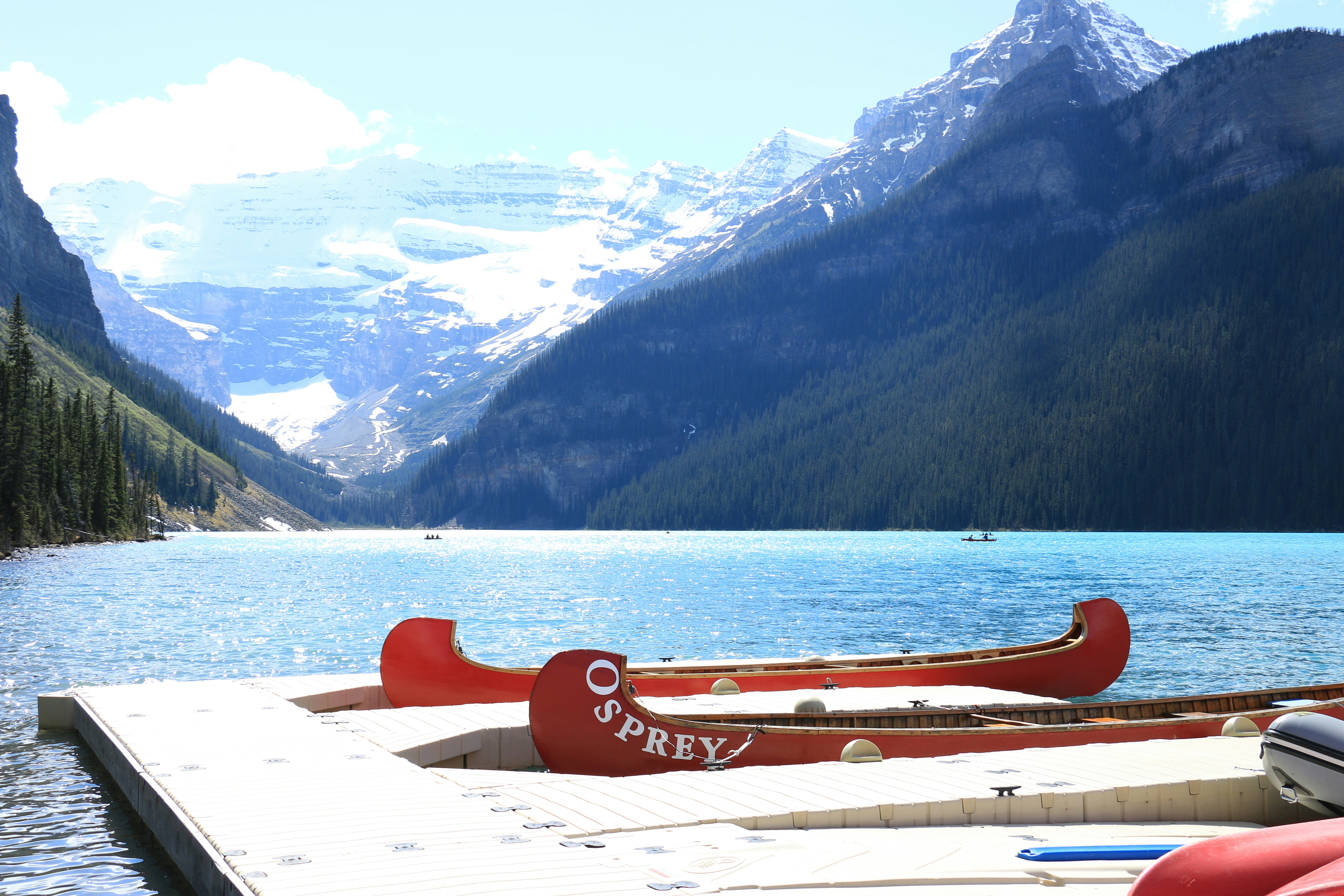 Two red canoes docked on a clear blue lake.