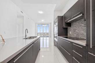 Modern dark wood kitchen with white countertops and island.