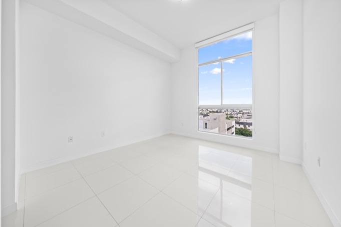 Empty white room with a large window overlooking city