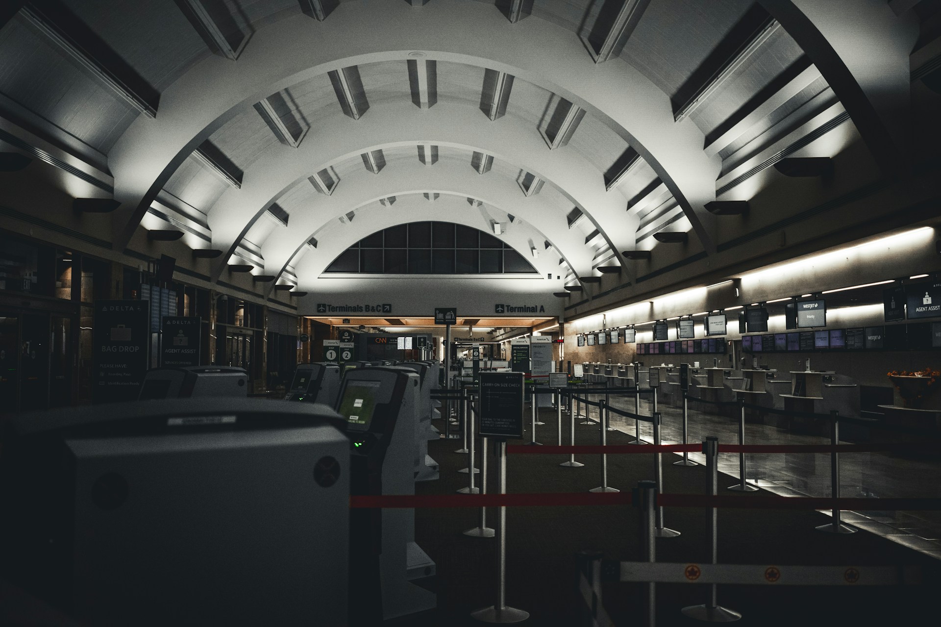 Empty airport terminal with rows of check-in counters.