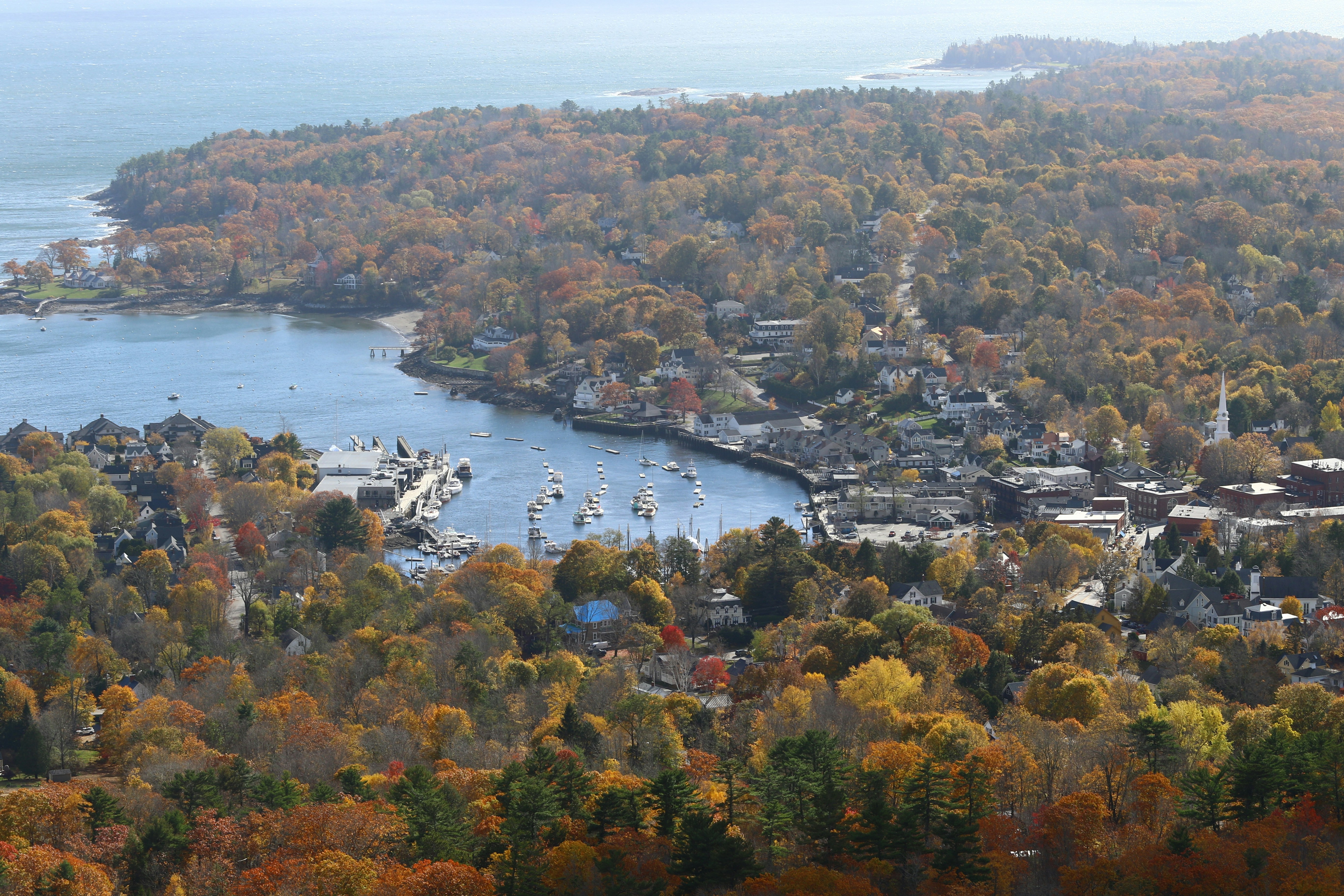 Coastal town nestled among autumn trees and bay.