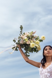 Woman holding a bouquet against a cloudy sky