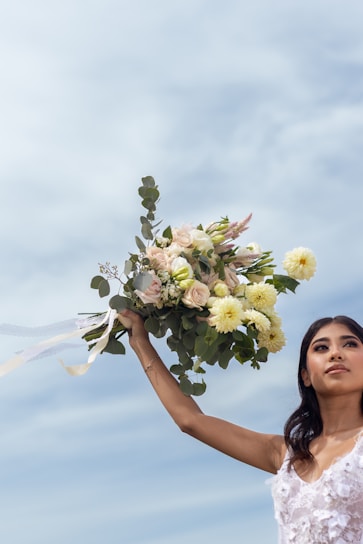Woman holding a bouquet against a cloudy sky