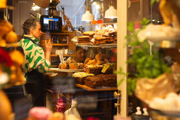 Person looking at baked goods in a shop window.