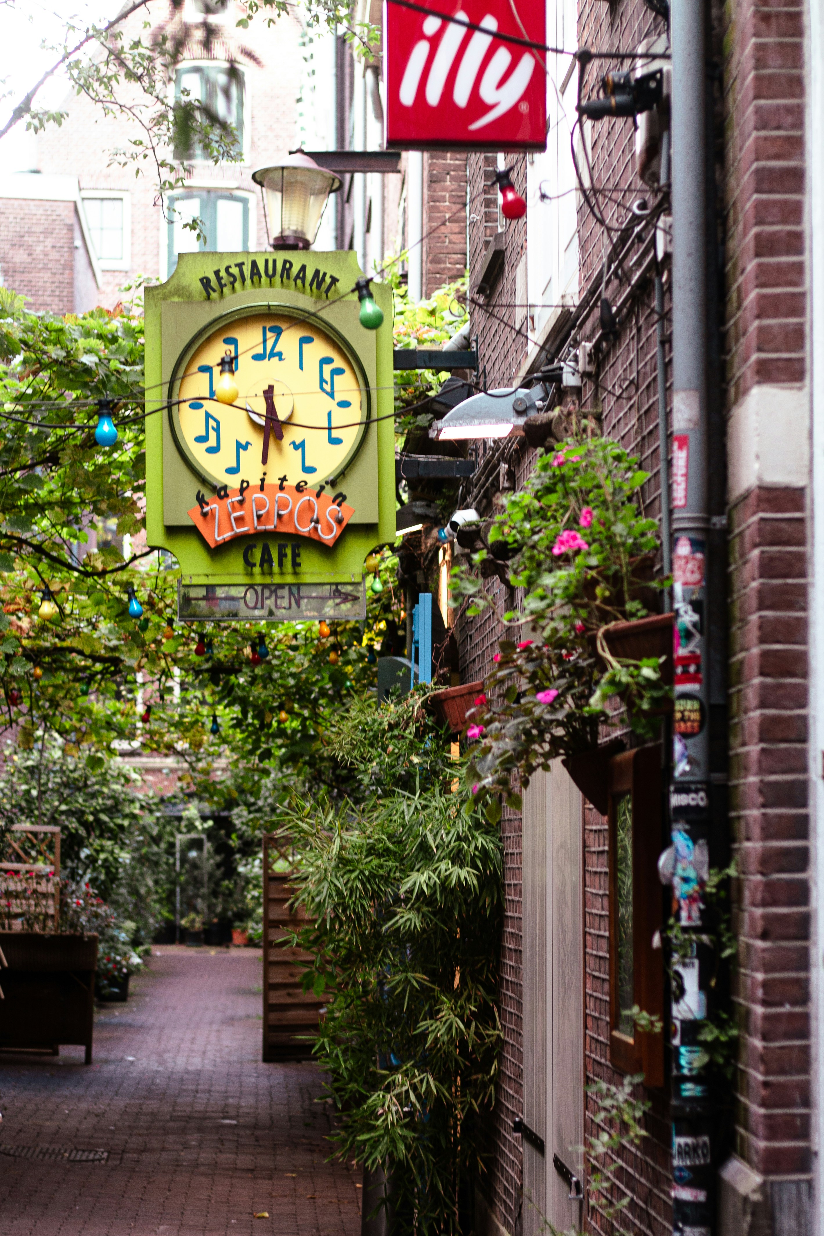 A quaint alley with a cafe sign and clock.