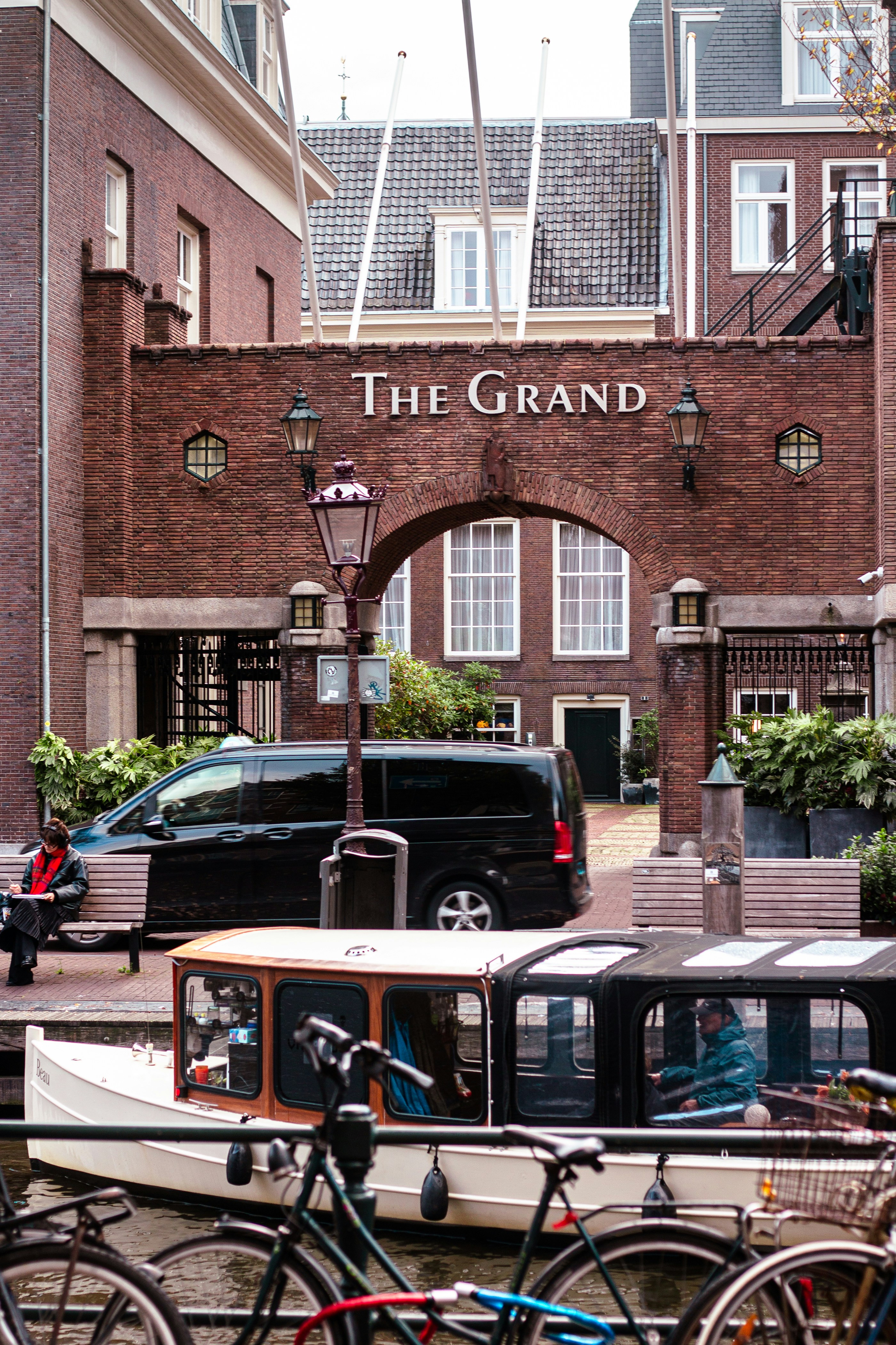 Canal scene with boats, bicycles, and building entrance.