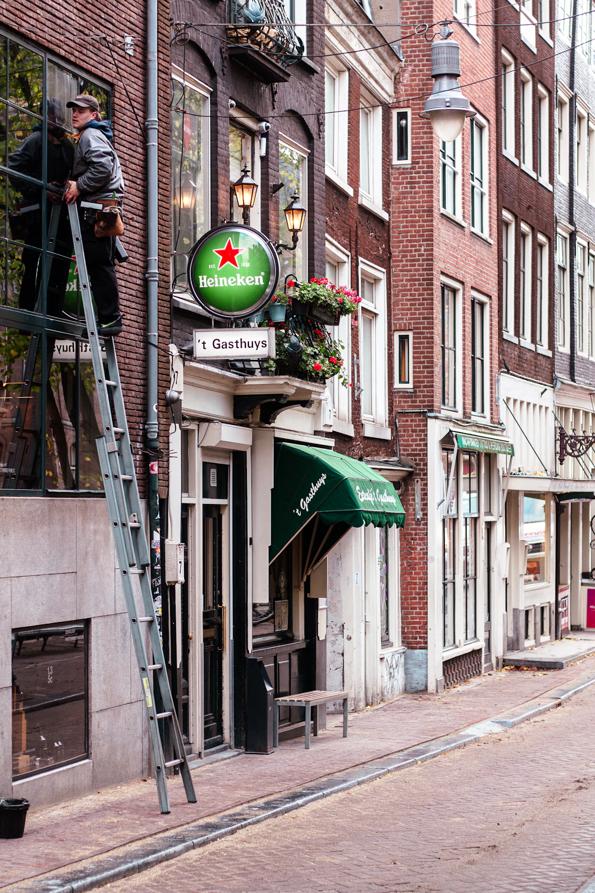 Glazenwasser op een ladder maakt de ramen van een winkelpui schoon