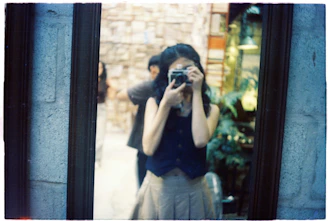 Woman takes a mirror selfie with a vintage camera.