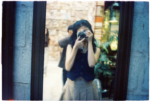 Woman takes a mirror selfie with a vintage camera.